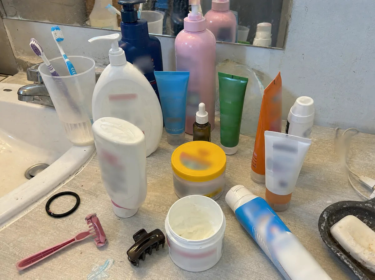 Repisa de baño con cremas y frascos a medio usar.